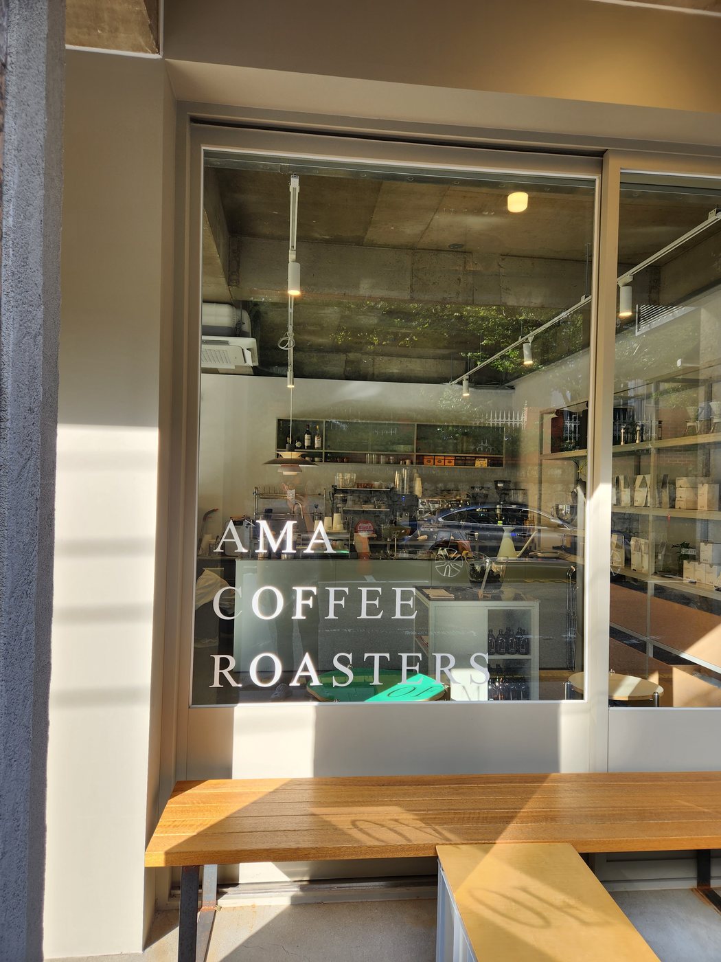AMA COFFEE ROASTERS 글씨가 있는 통창과 매장 앞 벤치